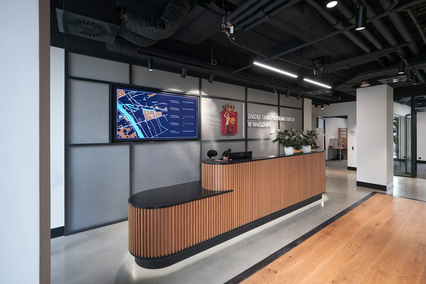 Receptionist at a modern desk with a city map screen.