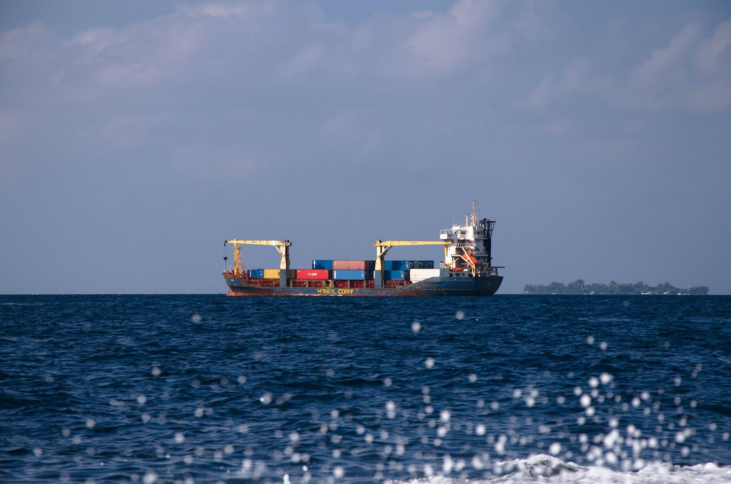 Cargo ship with shipping containers sails across the ocean.